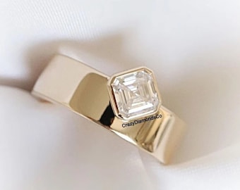 Cette version de la bague de fiançailles Off-Side est fabriquée avec une lunette sertie de 1,25 CT Asscher Cut Moissanite, le diamant serti dans un coin sur une large bande.