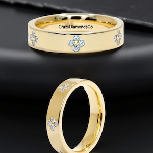 May include: A gold-colored ring with a flat band, featuring four-petal flower designs set with small, clear gemstones. The ring has the text "CrazyDiamondsCo" engraved on the inside.
