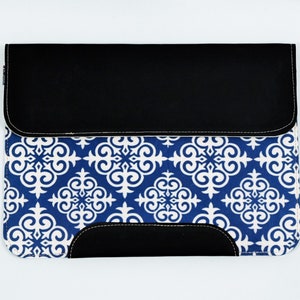 May include: A blue and white patterned laptop sleeve with a black leather flap. The pattern features a repeating design of white swirls on a blue background.
