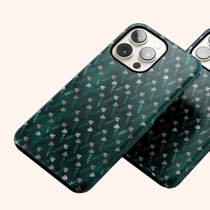 May include: Two green phone cases with a silver floral pattern. The cases are made of a clear material and have a raised edge around the camera lens.
