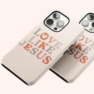 May include: Two white iPhone cases with a black border. The cases have a design of the words "LOVE LIKE JESUS" in a gradient of pink, orange, and brown. The words are stacked vertically with a heart symbol between "LOVE" and "LIKE".