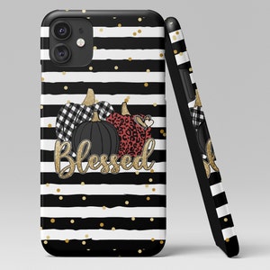 Puede incluir: Carcasa de tel&eacute;fono a rayas blancas y negras con purpurina dorada y tres calabazas. Las calabazas est&aacute;n decoradas con cuadros negros y blancos, estampado de leopardo y un coraz&oacute;n rojo. El texto "Blessed" est&aacute; escrito en purpurina dorada.