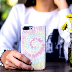 May include: A white phone case with a colorful tie-dye pattern. The pattern is a swirl of pink, blue, yellow, and white.