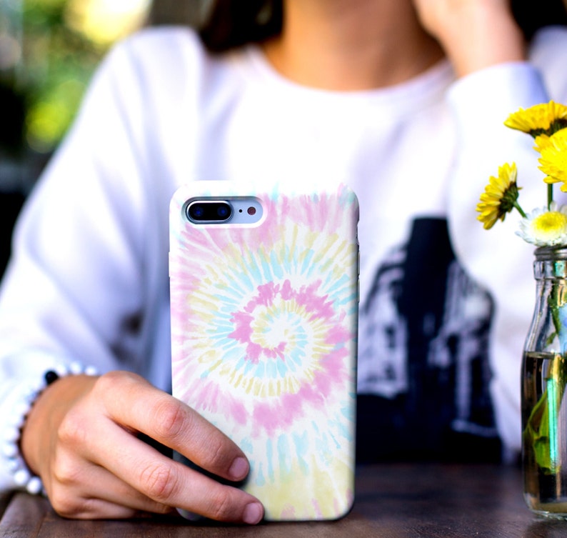 May include: A white phone case with a colorful tie-dye pattern. The pattern is a swirl of pink, blue, yellow, and white.
