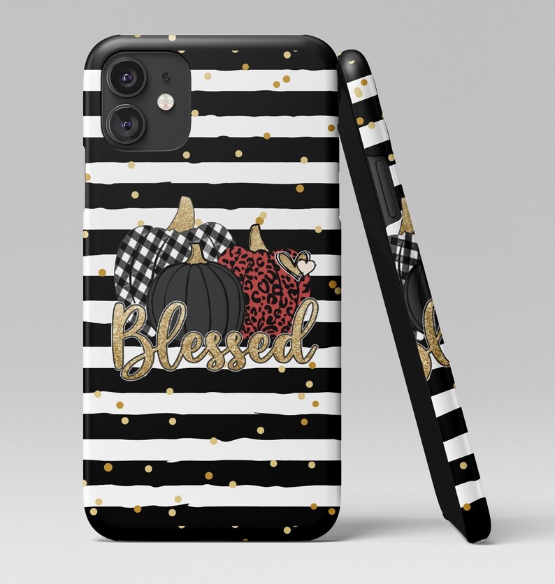 Puede incluir: Carcasa de tel&eacute;fono a rayas blancas y negras con purpurina dorada y tres calabazas. Las calabazas est&aacute;n decoradas con cuadros negros y blancos, estampado de leopardo y un coraz&oacute;n rojo. El texto "Blessed" est&aacute; escrito en purpurina dorada.