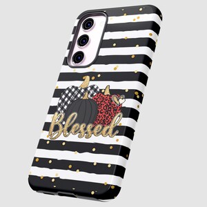 Puede incluir: Funda de tel&eacute;fono a rayas blancas y negras con purpurina dorada y un dise&ntilde;o de tres calabazas con la palabra "Blessed" en purpurina dorada.