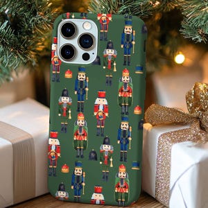 May include: A green phone case with a repeating pattern of nutcracker figurines. The nutcrackers are wearing traditional costumes and holding various props, such as drums, trumpets, and swords. The case has a cutout for the phone's camera lens.