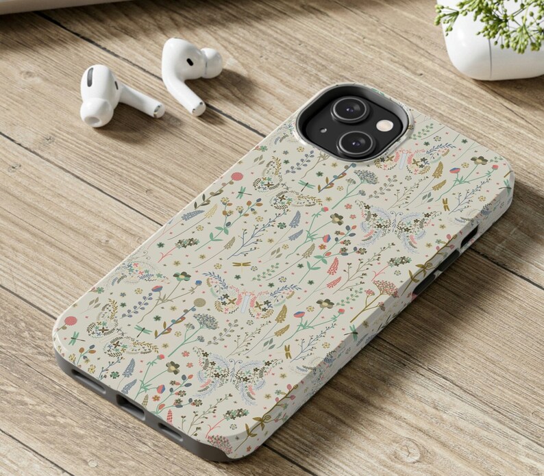 Puede incluir: Una funda de tel&eacute;fono blanca con un patr&oacute;n floral con mariposas y peque&ntilde;as flores. La funda tiene un recorte para el objetivo de la c&aacute;mara y un fondo crema.