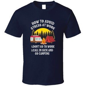 May include: A navy blue t-shirt with a white graphic design of a camper van, a campfire, and a tent. The text on the shirt reads "How to Avoid Stress at Work 1. Don't Go to Work 2. Call in Sick and Go Camping."