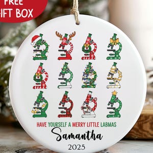 May include: A white ceramic Christmas ornament featuring twelve decorated microscopes. The ornament has the text "Have yourself a Merry Little Labmas" and a name, with the year 2025. A red banner at the top says "FREE GIFT BOX".