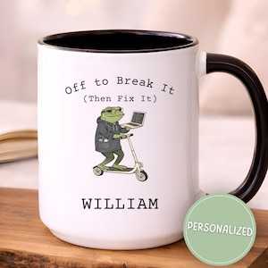 May include: White ceramic mug with a black handle and rim. The mug features a cartoon frog riding a scooter and holding a laptop, with the text "Off to Break It (Then Fix It)" and the name "WILLIAM". A green "PERSONALIZED" sticker is on the side.