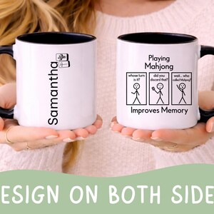 May include: White ceramic mug with a black interior and handle. One side features the name "Samantha" in black, and the other side has a Mahjong-themed design with stick figures and the text "Playing Mahjong Improves Memory."