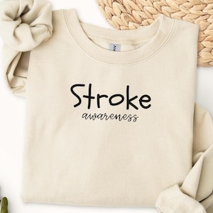 May include: A beige sweatshirt with the text "Stroke awareness" printed in black.