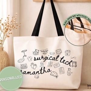 May include: A cream-colored canvas tote bag with black handles, featuring black line art illustrations of surgical equipment, the text "surgical tech" and "Samantha," and a circular inset showing a black zipper and an interior pocket.