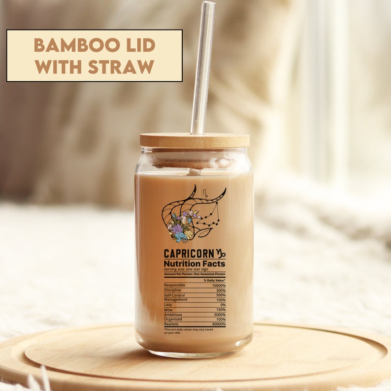 May include: A clear glass jar with a bamboo lid and a straw. The jar features a graphic of the Capricorn star sign with flowers and the text "CAPRICORN Nutrition Facts" with a list of personality traits and their percentage daily value.
