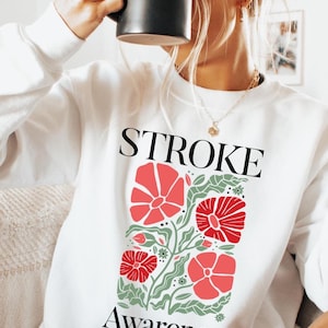 May include: White sweatshirt with a floral design and the text "STROKE Awareness".