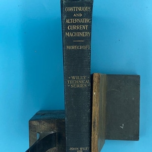 May include: A vintage hardcover book titled "Continuous and Alternating Current Machinery" by Morecroft. The book is part of the Wiley Technical Series and published by John Wiley and Sons, Inc.