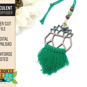May include: A green tassel hangs from a wooden geometric cutout shaped like a succulent plant. The cutout is attached to a string with brown wooden beads and a small metal charm of a succulent plant. The text "SUCCULENT CAR DIFFUSER" is visible in the top left corner of the image.