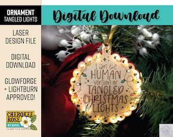 May include: A round wooden Christmas ornament featuring a scalloped edge and laser-engraved text that reads I am the HUMAN version of TANGLED CHRISTMAS LIGHTS. The ornament is illuminated by small, warm-toned LED string lights.