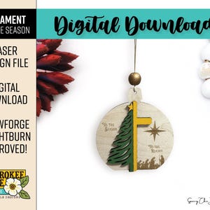 Puede incluir: Un adorno navide&ntilde;o redondo de madera con un pino verde cortado a l&aacute;ser, una cruz amarilla y una estrella. El adorno muestra el texto 'Tis the Season' y 'Tis the Reason' junto a una silueta de un bel&eacute;n. Cuelga de una cuenta dorada.