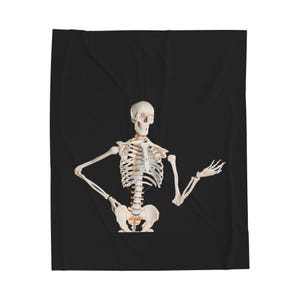 May include: A white human skeleton model with arms outstretched, set against a black background. The model is anatomically correct, showing the skull, rib cage, spine, and pelvic bones. The skeleton is a medical or educational item.