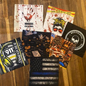 May include: A collection of seven square microfiber cleaning cloths featuring various graphic prints including a 911 dispatcher headset, a crime scene theme, a medicolegal investigator skull logo, a thin blue line flag, and holiday designs.