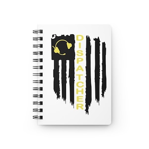 May include: A white spiral-bound notebook featuring a black distressed flag graphic on the cover. The design includes a yellow headset icon in the upper left corner and the word DISPATCHER printed vertically in yellow capital letters.
