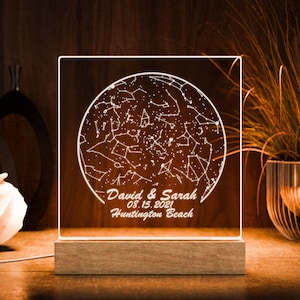 May include: A white acrylic night light with a star map design. The map shows the constellations as they appeared on August 15, 2021, in Huntington Beach, California. The text "David & Sarah" is inscribed below the map.