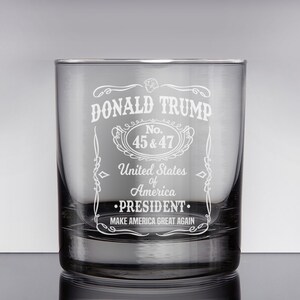 Peut inclure: Un verre &agrave; whisky en verre transparent avec un motif grav&eacute; repr&eacute;sentant le texte "DONALD TRUMP", "No. 45 & 47", "United States of America", "&bull;PRESIDENT.", et "MAKE AMERICA GREAT AGAIN".