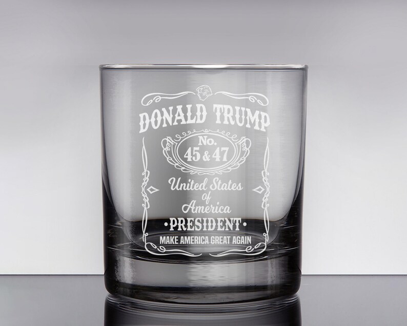 Peut inclure: Un verre &agrave; whisky en verre transparent avec un motif grav&eacute; repr&eacute;sentant le texte "DONALD TRUMP", "No. 45 & 47", "United States of America", "&bull;PRESIDENT.", et "MAKE AMERICA GREAT AGAIN".
