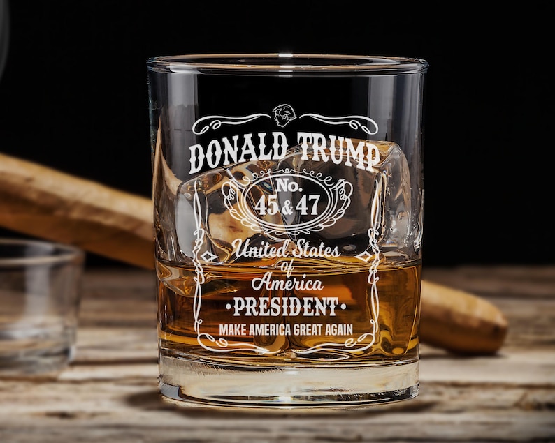 Peut inclure: Un verre &agrave; whisky en verre transparent avec un motif blanc qui dit "DONALD TRUMP No. 45 & 47 United States of America &bull;PRESIDENT. MAKE AMERICA GREAT AGAIN".