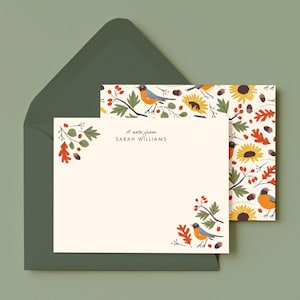 May include: A cream-colored stationery card with the text A note from SARAH WILLIAMS, featuring illustrations of robins, sunflowers, oak leaves, and berries in the corners, paired with a matching patterned envelope in dark olive green.
