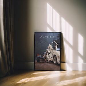 May include: A framed poster of a scene from "The Wolf of Wall Street." The image depicts a white sports car with an open door and a person in a suit. The poster is propped against a white wall, with the text "THE WOLF OF WALL STREET" at the top.