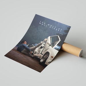 May include: Poster print of a scene from "The Wolf of Wall Street" with a white sports car and a man in a blue jacket. The title is printed at the top. The poster is rolled and placed next to a cardboard tube.