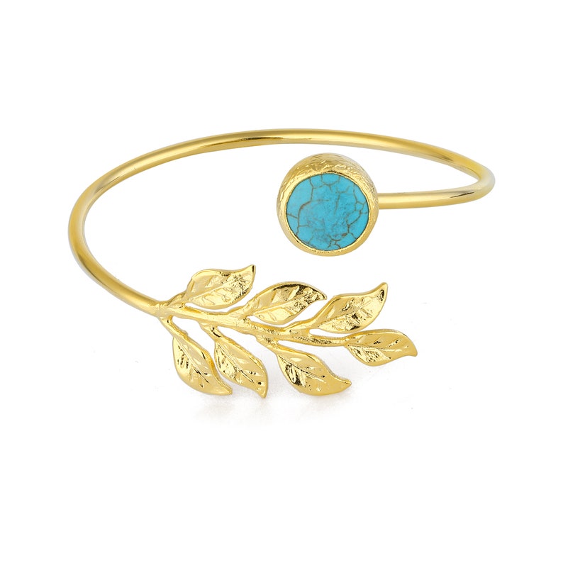 May include: Gold bangle bracelet with a turquoise stone and a leaf design.
