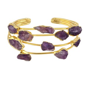 May include: Gold bangle bracelet with multiple rows of amethyst gemstones. The bracelet is made of thin gold wire and features several amethyst stones of varying sizes and shapes.