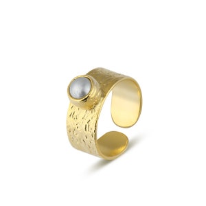 May include: Gold adjustable ring with a textured band and a white pearl-like stone.