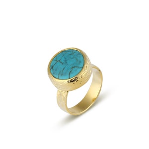 May include: A gold ring with a turquoise stone set in a textured band.