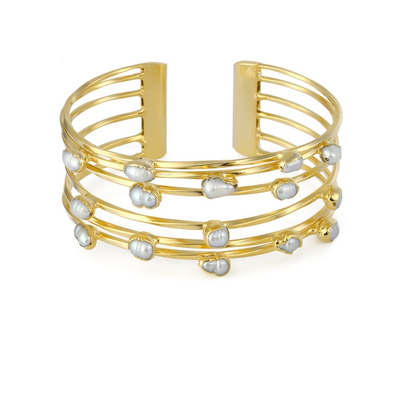 May include: Gold bangle bracelet with five rows of metal and white pearl accents.