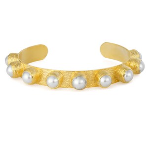 May include: A gold bangle bracelet with a textured surface and white pearl accents.
