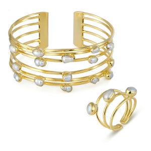 May include: A gold bangle bracelet with five bands and a ring with three bands, both adorned with irregular white pearls.
