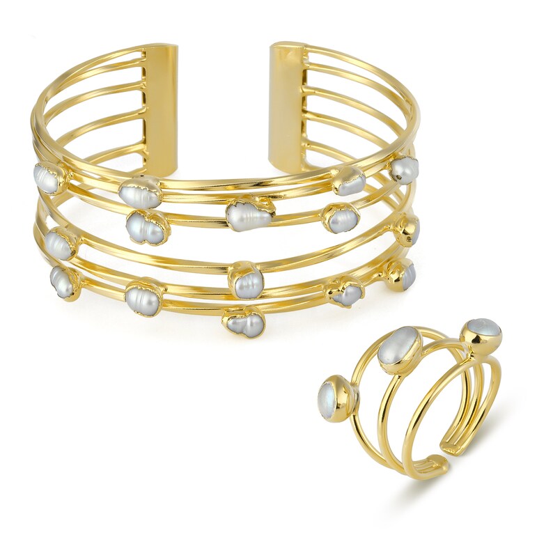 May include: A gold bangle bracelet with five bands and a ring with three bands, both adorned with irregular white pearls.