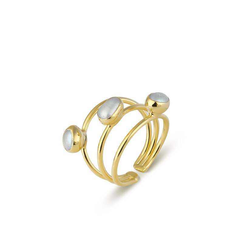 May include: Gold ring with three oval-shaped moonstone gems. The ring is adjustable and has a simple, minimalist design.
