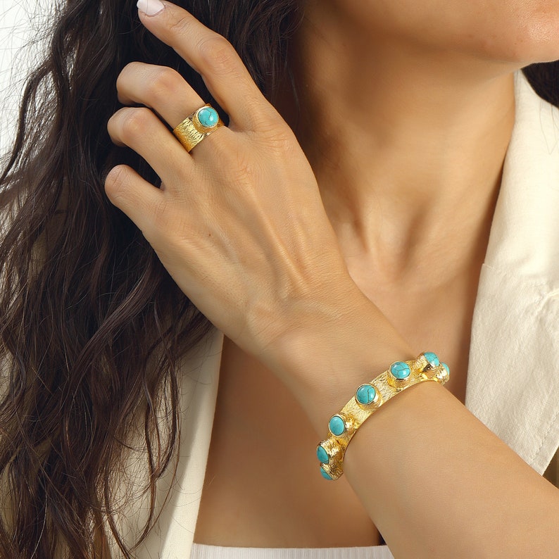 May include: A gold bracelet with turquoise stones and a matching gold ring with a turquoise stone.