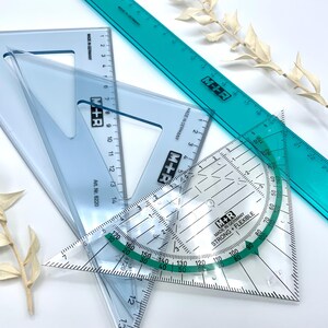 Könnte beinhalten: Drei transparente Kunststofflineale, zwei Dreiecke und ein langes Lineal. Die Lineale sind mit Zahlen gekennzeichnet und haben einen grünen Rand. Die Lineale werden von M+R hergestellt und tragen die Aufschrift "Made in Germany" und "Strong + Flexible".