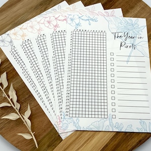 Könnte beinhalten: Vier bedruckbare Blätter mit Blumendesigns und einem Raster zum Verfolgen täglicher Gewohnheiten. Das Blatt rechts trägt den Text "The Year in Pixels" und eine Liste leerer Kästchen.
