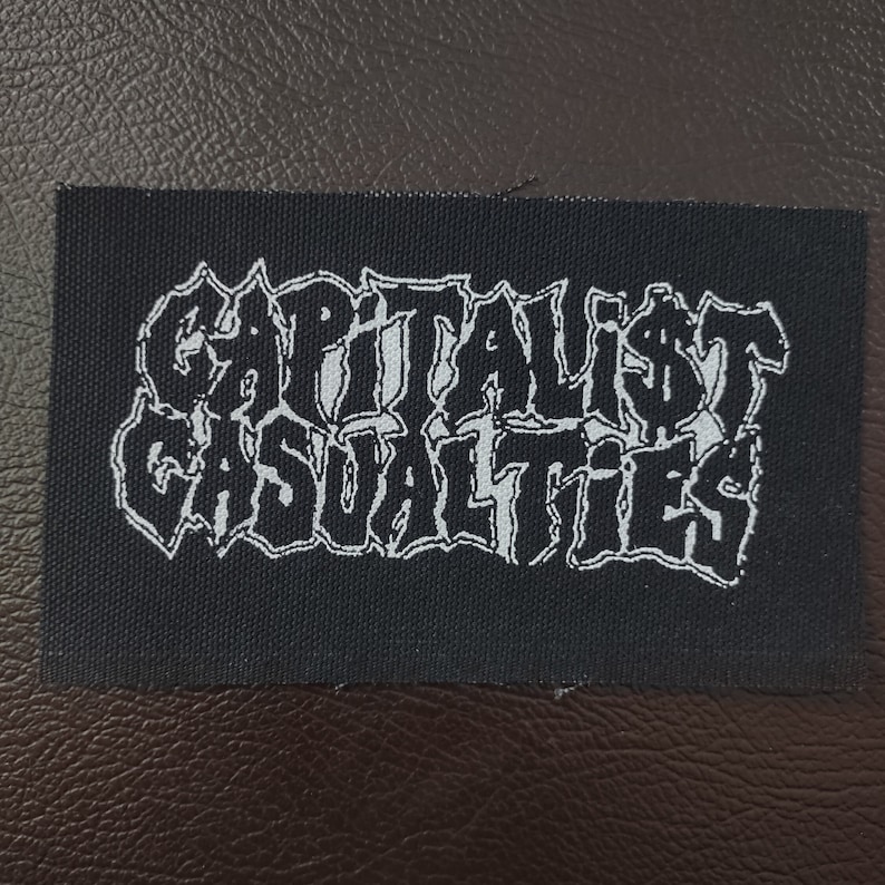 May include: A black patch with the words "Capitalist Casualties" in white, stylized text.
