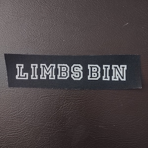 May include: A black fabric label with white text that reads "LIMBS BIN".