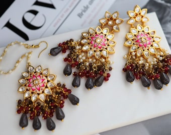 May include: A set of gold earrings with a floral design and a dangling chain of gray, brown, and red beads. The earrings are accented with clear stones.
