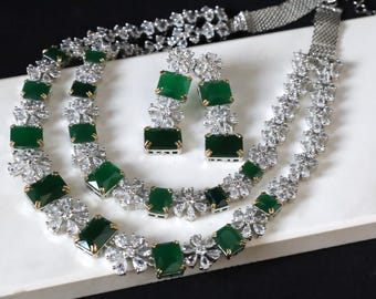 May include: A silver and green necklace and earrings set with a double strand of cubic zirconia stones and emerald green square-shaped stones.